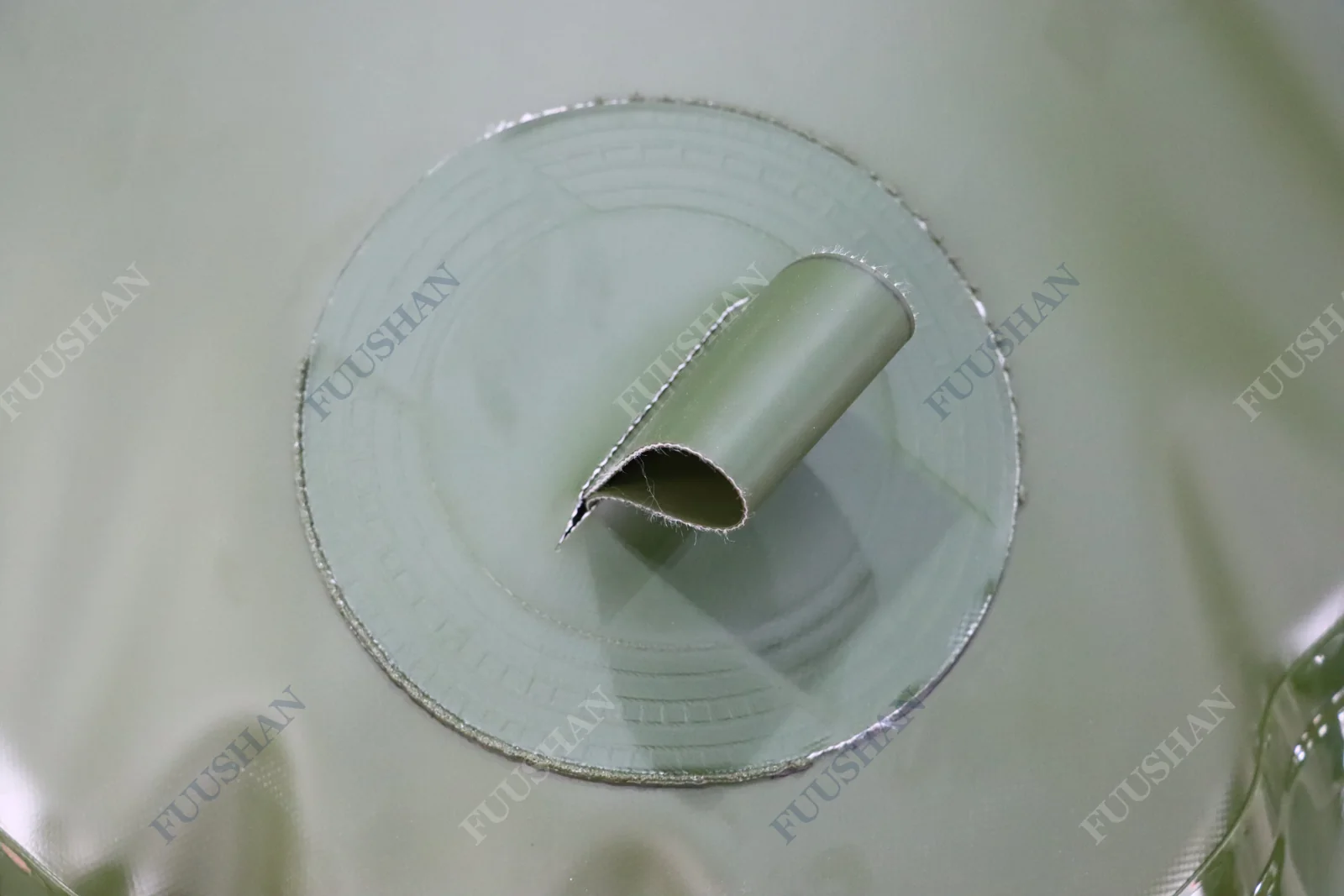 Fabric handle attached to a reinforced circular patch on green tank fabric